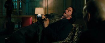 Movie still from “John Wick: Chapter 3 - Parabellum” (2019), directed by Chad Stahelski – A man laying in a chair with a dog; Medium shot, High angle