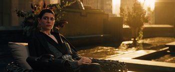 Movie still from “John Wick: Chapter 3 - Parabellum” (2019), directed by Chad Stahelski – A woman sitting on a chair in a city setting; Medium shot, Over the shoulder angle