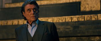 Movie still from “John Wick: Chapter 3 - Parabellum” (2019), directed by Chad Stahelski – An older man in a suit standing in front of a wall; Close Up shot, Low angle