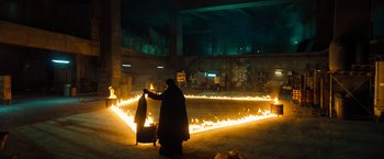 Movie still from “John Wick: Chapter 4” (2023), directed by Chad Stahelski – A person standing in front of a fire pit at night; Extreme Wide shot, High angle