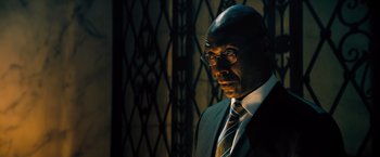 Movie still from “John Wick: Chapter 4” (2023), directed by Chad Stahelski – A man in a suit and tie standing next to a wall; Close Up shot, Low angle