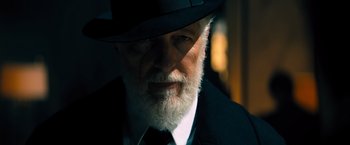 Movie still from “John Wick: Chapter 4” (2023), directed by Chad Stahelski – An old man with a beard wearing a suit and a hat; Close Up shot, Low angle