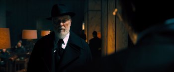 Movie still from “John Wick: Chapter 4” (2023), directed by Chad Stahelski – An older man in a hat and a coat; Medium shot, Over the shoulder angle