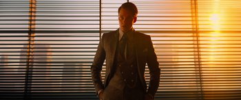 Movie still from “John Wick: Chapter 4” (2023), directed by Chad Stahelski – A man in a suit and tie standing in front of a window; Medium shot, Low angle