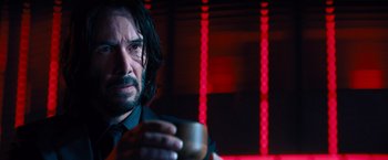 Movie still from “John Wick: Chapter 4” (2023), directed by Chad Stahelski – A man holding a coffee cup in a dark room; Close Up shot, Over the shoulder angle