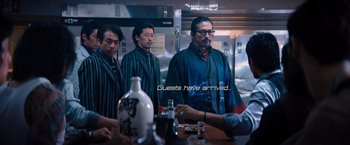 Movie still from “John Wick: Chapter 4” (2023), directed by Chad Stahelski – A group of men standing around a table; Medium shot, Low angle