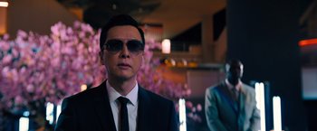 Movie still from “John Wick: Chapter 4” (2023), directed by Chad Stahelski – A man in a suit and tie wearing sunglasses; Medium shot, Low angle