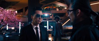 Movie still from “John Wick: Chapter 4” (2023), directed by Chad Stahelski – A man in a suit and sunglasses standing next to another man in a suit and sunglasses; Medium shot, Over the shoulder angle