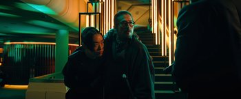Movie still from “John Wick: Chapter 4” (2023), directed by Chad Stahelski – A man standing next to a woman in front of a staircase; Medium shot, Low angle
