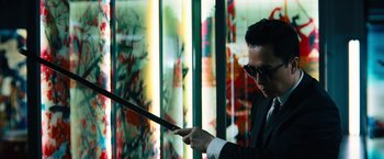 Movie still from “John Wick: Chapter 4” (2023), directed by Chad Stahelski – A man in a suit and sunglasses holding a sword; Medium shot, Low angle
