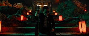Movie still from “John Wick: Chapter 4” (2023), directed by Chad Stahelski – A man sitting on the ground holding a cane; Medium shot, Low angle