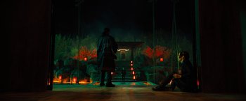 Movie still from “John Wick: Chapter 4” (2023), directed by Chad Stahelski – A man standing in front of a stage at night; Extreme Wide shot, High angle