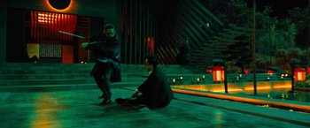 Movie still from “John Wick: Chapter 4” (2023), directed by Chad Stahelski – Two men are sitting on the ground in the dark; Wide shot, High angle