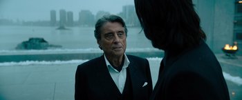 Movie still from “John Wick: Chapter 4” (2023), directed by Chad Stahelski – An older man wearing a suit and a tie; Close Up shot, Over the shoulder angle