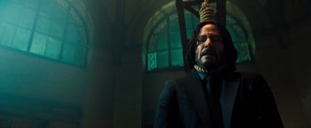 Movie still from “John Wick: Chapter 4” (2023), directed by Chad Stahelski – A man in a suit and tie wearing a head piece; Close Up shot, Low angle