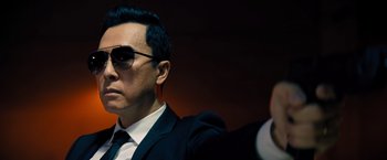 Movie still from “John Wick: Chapter 4” (2023), directed by Chad Stahelski – A man in a suit and tie wearing sunglasses; Close Up shot, Low angle