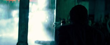 Movie still from “John Wick: Chapter 4” (2023), directed by Chad Stahelski – A person standing in front of a wall with smoke coming out of it; Close Up shot, Over the shoulder angle