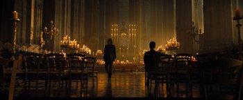 A person walking in a room lit up by candles