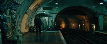 Movie still from “John Wick: Chapter 4” (2023), directed by Chad Stahelski – A man standing in front of a train platform; Extreme Wide shot, Low angle