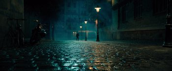 Movie still from “John Wick: Chapter 4” (2023), directed by Chad Stahelski – A person is walking on a cobblestone street at night; Extreme Wide shot, High angle