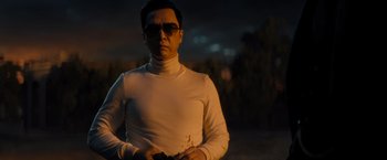 Movie still from “John Wick: Chapter 4” (2023), directed by Chad Stahelski – A man in white shirt and sunglasses holding a gun; Medium shot, Low angle