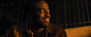 Movie still from “John Wick: Chapter 4” (2023), directed by Chad Stahelski – A person with a beard smiling; Close Up shot, Low angle