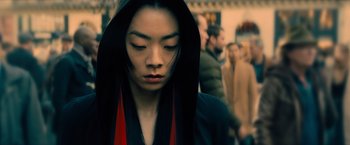 Movie still from “John Wick: Chapter 4” (2023), directed by Chad Stahelski – A person with a hooded jacket is standing in the street; Close Up shot, Over the shoulder angle