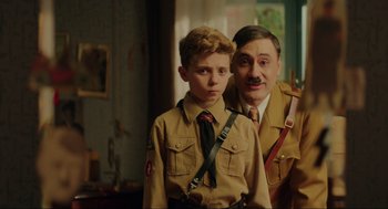 Movie still from “Jojo Rabbit” (2019), directed by Taika Waititi – A man and a young boy dressed as hitler and mussolini; Medium shot, Over the shoulder angle