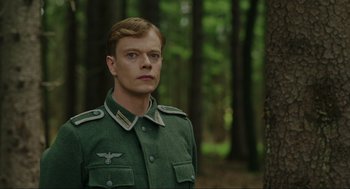 Movie still from “Jojo Rabbit” (2019), directed by Taika Waititi – A man in a green uniform standing next to a tree; Close Up shot, Low angle