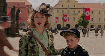 Movie still from “Jojo Rabbit” (2019), directed by Taika Waititi – A woman and a boy are standing in front of a building; Medium shot, Low angle