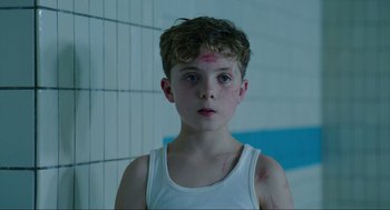 Movie still from “Jojo Rabbit” (2019), directed by Taika Waititi – A young boy in a white shirt with a red spot on his forehead; Close Up shot, Over the shoulder angle