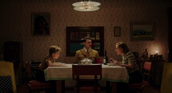 Movie still from “Jojo Rabbit” (2019), directed by Taika Waititi – A man and two women sitting at a dinner table; Wide shot, High angle