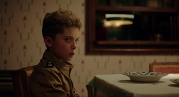 Movie still from “Jojo Rabbit” (2019), directed by Taika Waititi – A young boy sitting at a table with a bowl; Close Up shot, Over the shoulder angle