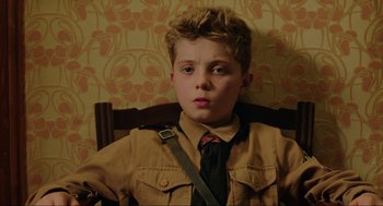 Movie still from “Jojo Rabbit” (2019), directed by Taika Waititi – A young boy in a uniform sitting in a chair; Close Up shot, High angle