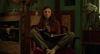 Movie still from “Jojo Rabbit” (2019), directed by Taika Waititi – A woman sitting in a chair holding a book; Medium shot, Low angle