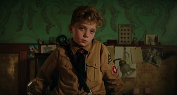 Movie still from “Jojo Rabbit” (2019), directed by Taika Waititi – A young boy in a uniform is posing for a picture; Close Up shot, High angle