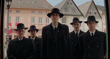 Movie still from “Jojo Rabbit” (2019), directed by Taika Waititi – A group of men in suits and hats standing in front of a building; Medium shot, Low angle