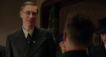 Movie still from “Jojo Rabbit” (2019), directed by Taika Waititi – A man in a suit and tie talking to another man; Medium shot, Over the shoulder angle