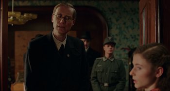 Movie still from “Jojo Rabbit” (2019), directed by Taika Waititi – A group of men standing next to each other in a room; Medium shot, Over the shoulder angle