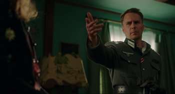 Movie still from “Jojo Rabbit” (2019), directed by Taika Waititi – A man in a military uniform holding his hand up; Medium shot, Low angle