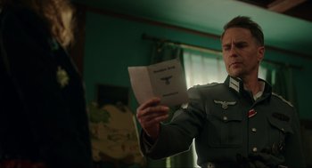 Movie still from “Jojo Rabbit” (2019), directed by Taika Waititi – A man in a military uniform holding a piece of paper in his hands; Medium shot, Over the shoulder angle