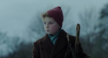 Movie still from “Jojo Rabbit” (2019), directed by Taika Waititi – A boy in a brown coat and a pink hat holding a stick; Close Up shot, Over the shoulder angle