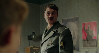 Movie still from “Jojo Rabbit” (2019), directed by Taika Waititi – A man in a military uniform standing in a room; Close Up shot, Over the shoulder angle