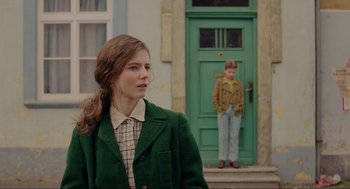 Movie still from “Jojo Rabbit” (2019), directed by Taika Waititi – A young woman standing in front of a green door; Medium shot, Over the shoulder angle