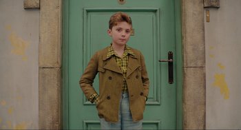 Movie still from “Jojo Rabbit” (2019), directed by Taika Waititi – A young boy standing in front of a green door; Medium shot, High angle