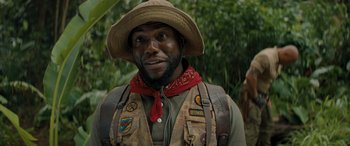 Movie still from “Jumanji: The Next Level” (2019), directed by Jake Kasdan – A man wearing a hat and a vest; Close Up shot, Over the shoulder angle