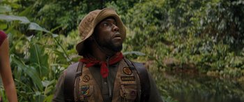 Movie still from “Jumanji: The Next Level” (2019), directed by Jake Kasdan – A man wearing a hat and vest looking up; Close Up shot, Low angle