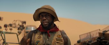Movie still from “Jumanji: The Next Level” (2019), directed by Jake Kasdan – A man with a beard and a hat is standing in the desert; Close Up shot, Low angle