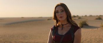 Movie still from “Jumanji: The Next Level” (2019), directed by Jake Kasdan – A beautiful woman standing on top of a sandy beach; Close Up shot, Over the shoulder angle
