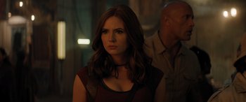 Movie still from “Jumanji: The Next Level” (2019), directed by Jake Kasdan – A woman in a red dress is standing in a dark room; Close Up shot, Over the shoulder angle